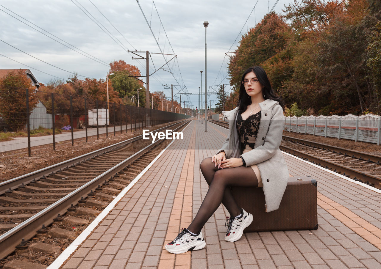 YOUNG WOMAN SITTING ON RAILROAD TRACKS