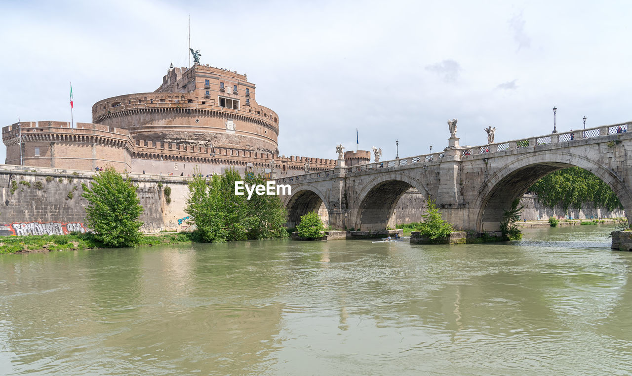 VIEW OF ARCH BRIDGE OVER RIVER AGAINST CLOUDY SKY