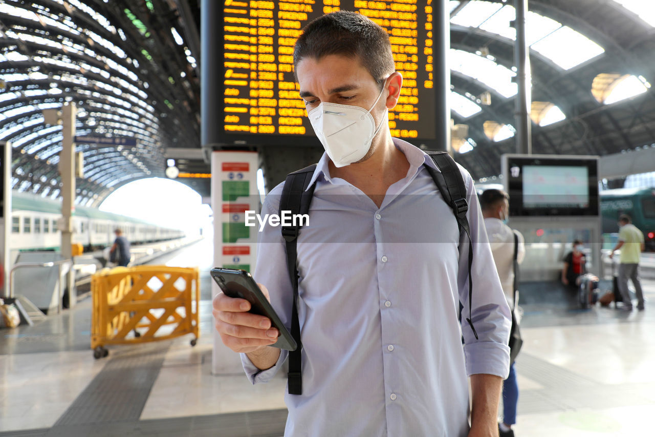 Man wearing mask and using mobile phone at airport