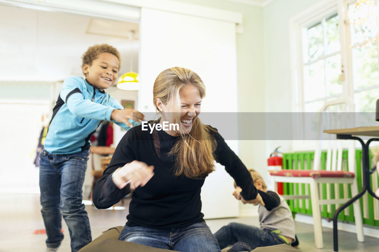 Happy teacher playing with boys in kindergarten