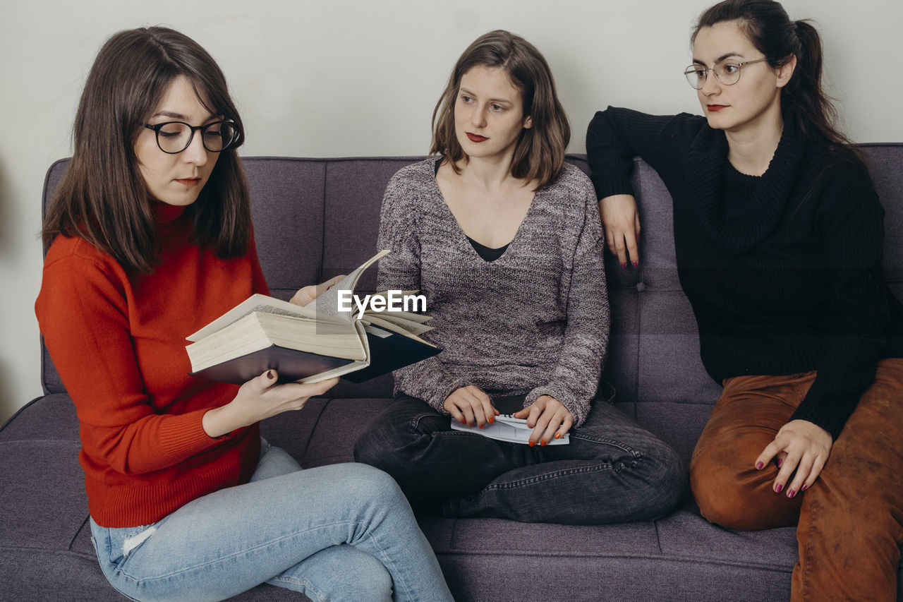 WOMEN SITTING ON SOFA AT HOME