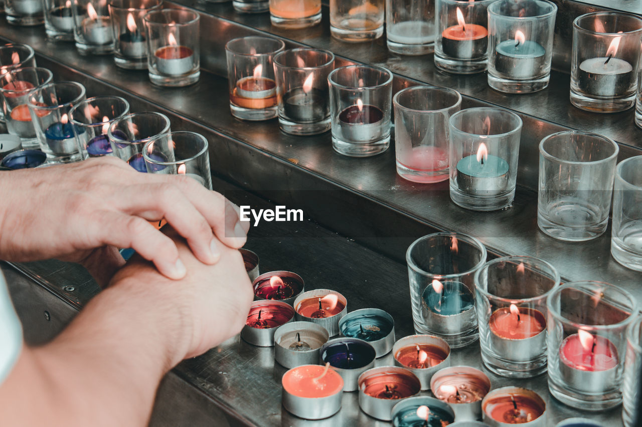 Cropped hands by lit tea light candles on steps