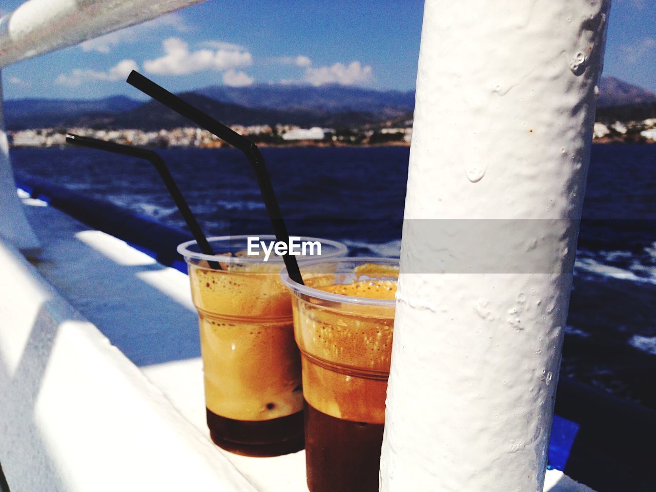 Close-up of espresso in disposable glasses with straws on railing