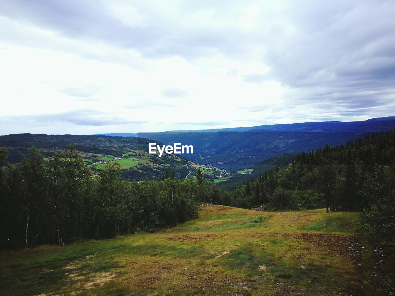 SCENIC SHOT OF COUNTRYSIDE LANDSCAPE AGAINST CLOUDS