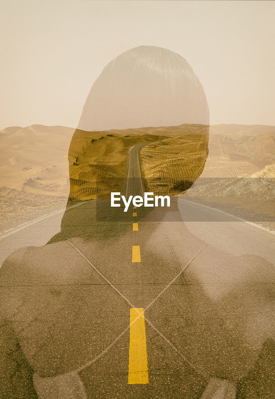 Double exposure image of woman and empty road against sky