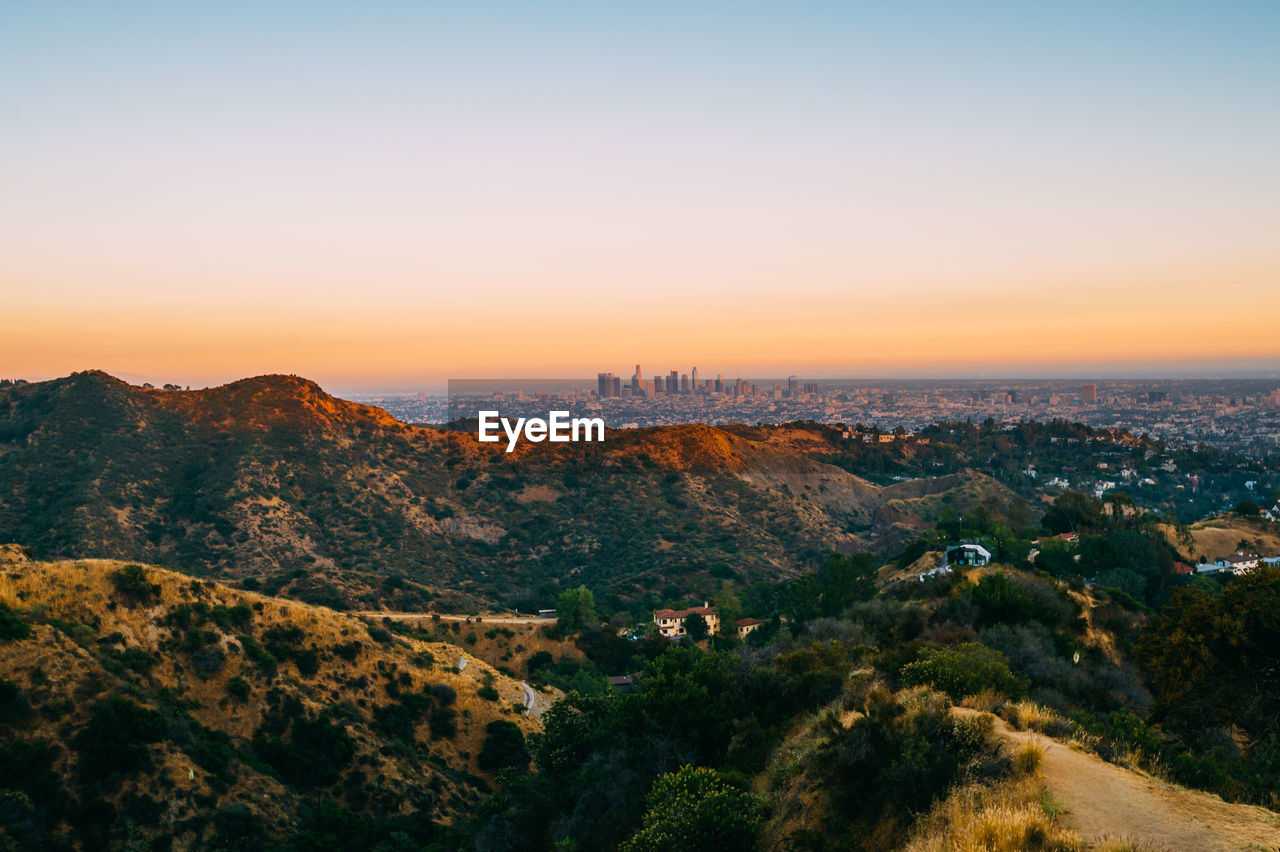 Scenic view of mountains and buildings against sky during sunset