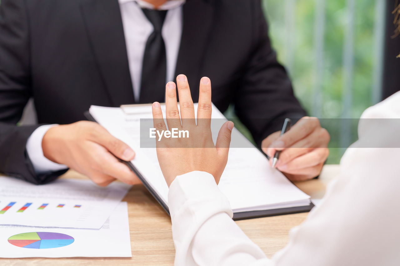 Close-up of business colleagues working at desk in office