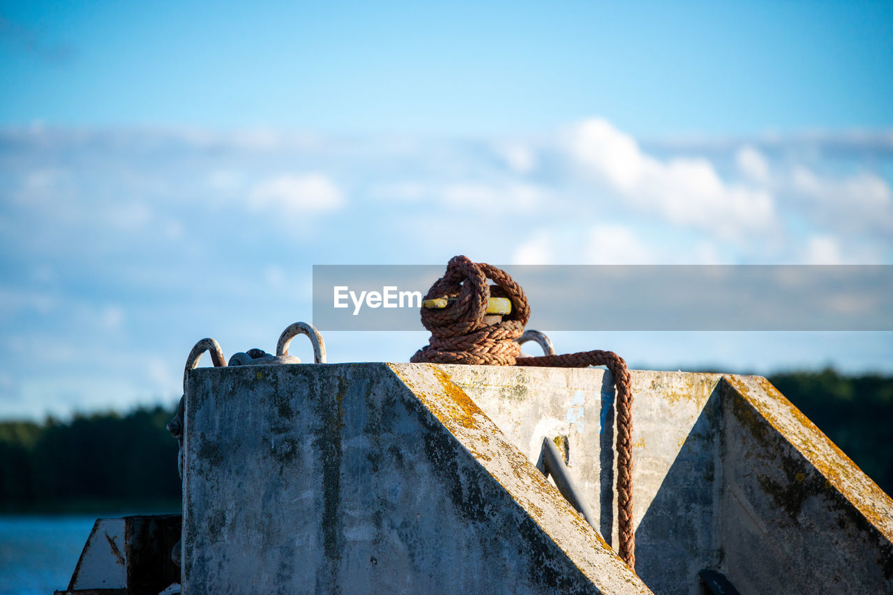 VIEW OF BIRD PERCHING ON RUSTY METAL AGAINST SEA