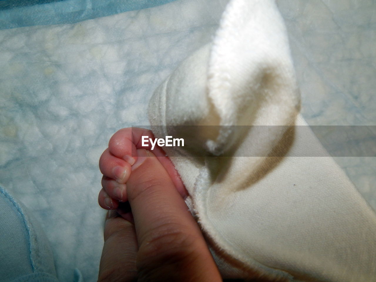 LOW SECTION OF BABY FEET WITH HAND ON CARPET