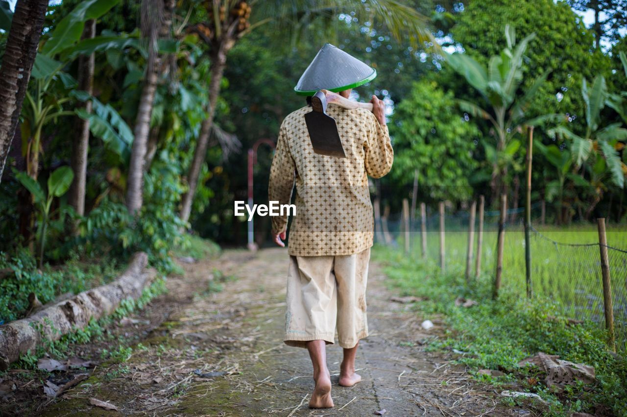 REAR VIEW OF WOMAN WALKING ON UMBRELLA