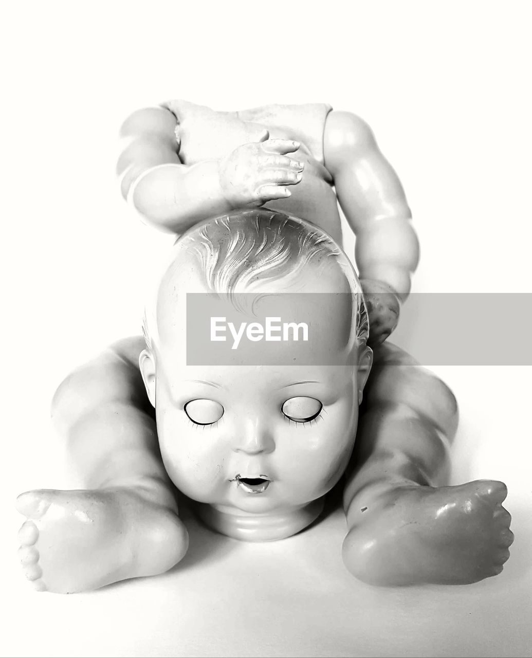 Close-up of baby figurine with separated head against white background