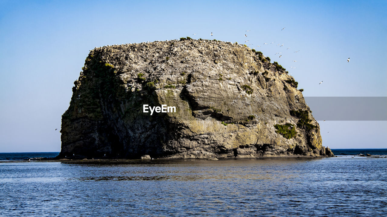 ROCK FORMATION IN SEA AGAINST SKY