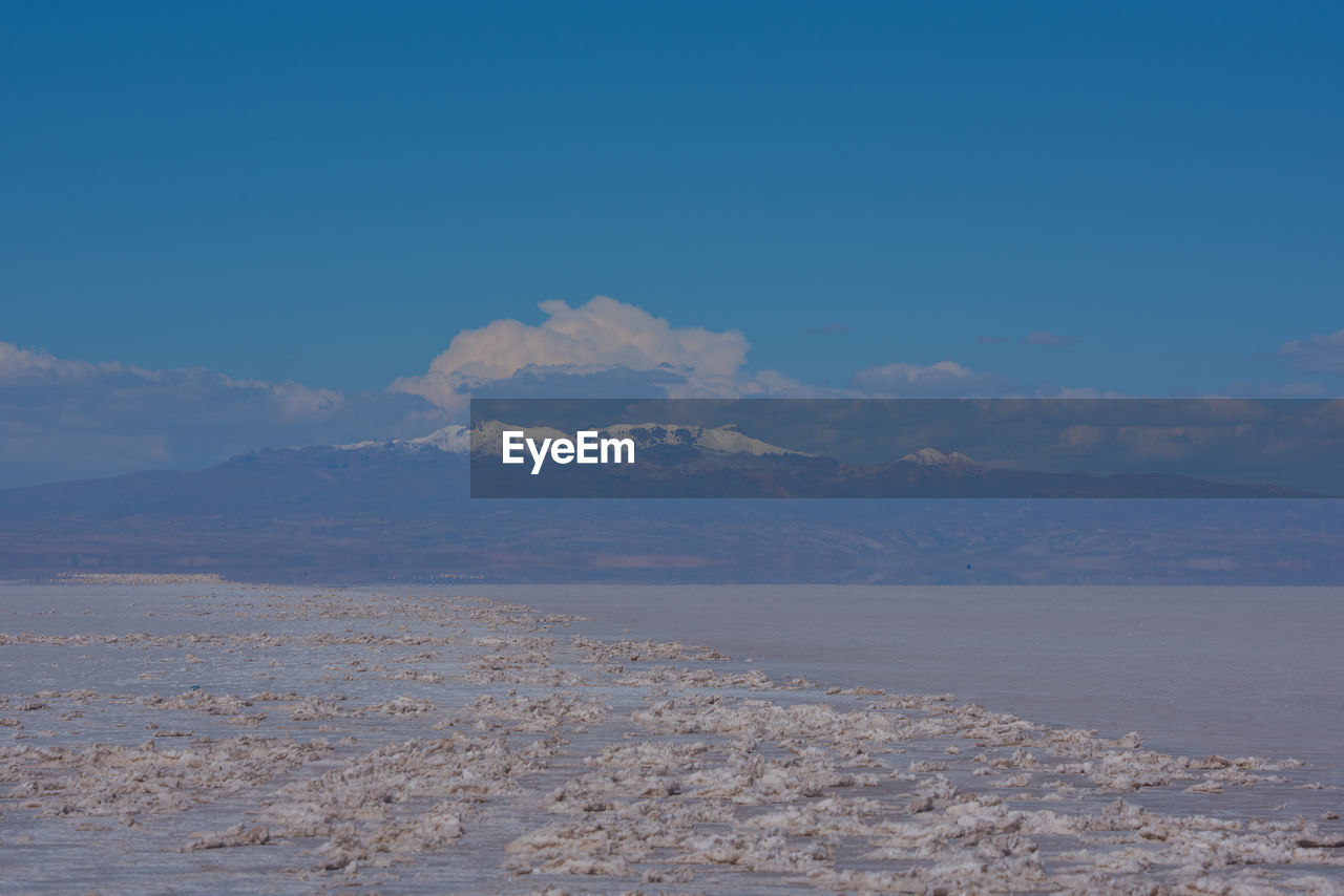 Scenic view of sea and mountains against blue sky