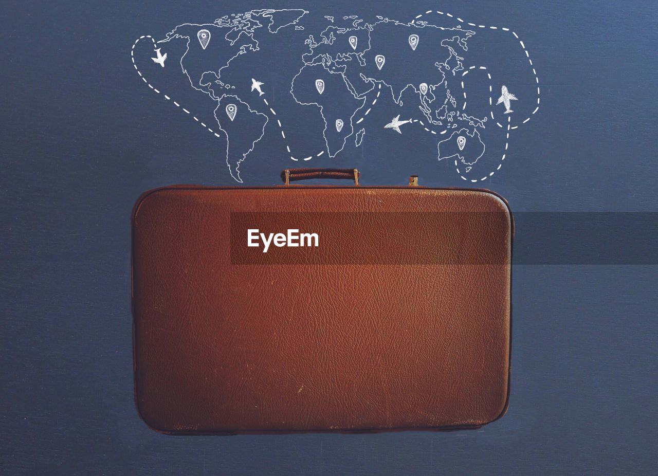 Brown suitcase against world map