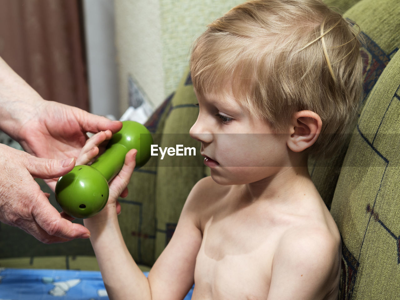 Shirtless boy holding dumbbell