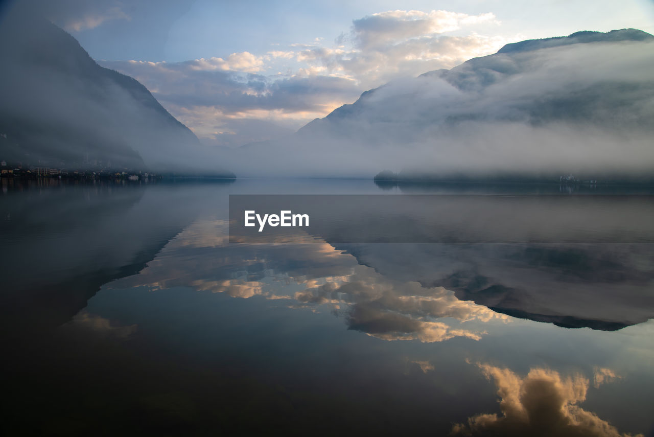 SCENIC VIEW OF LAKE AND MOUNTAINS AGAINST SKY AT SUNSET