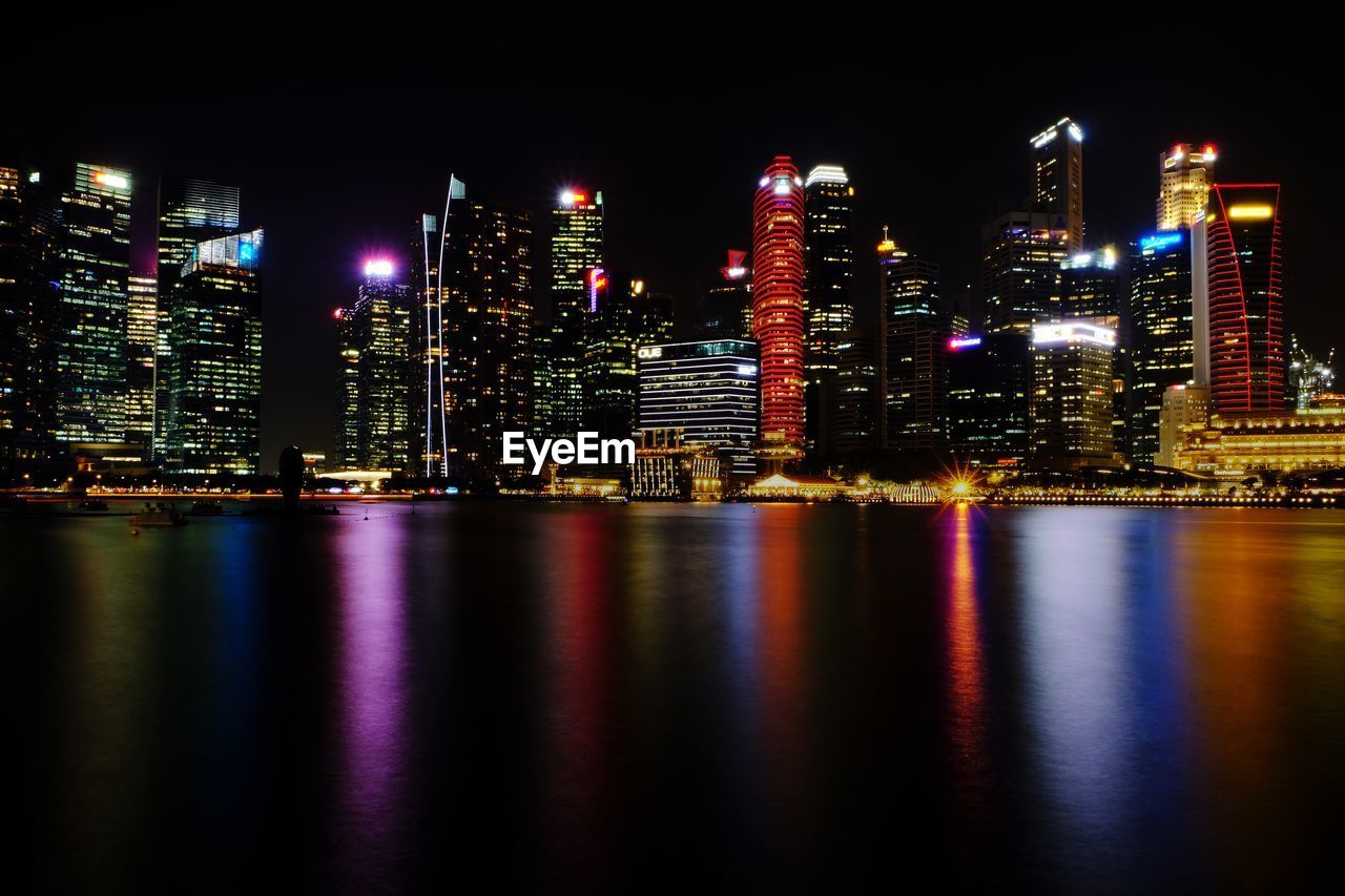 Illuminated buildings by river at night