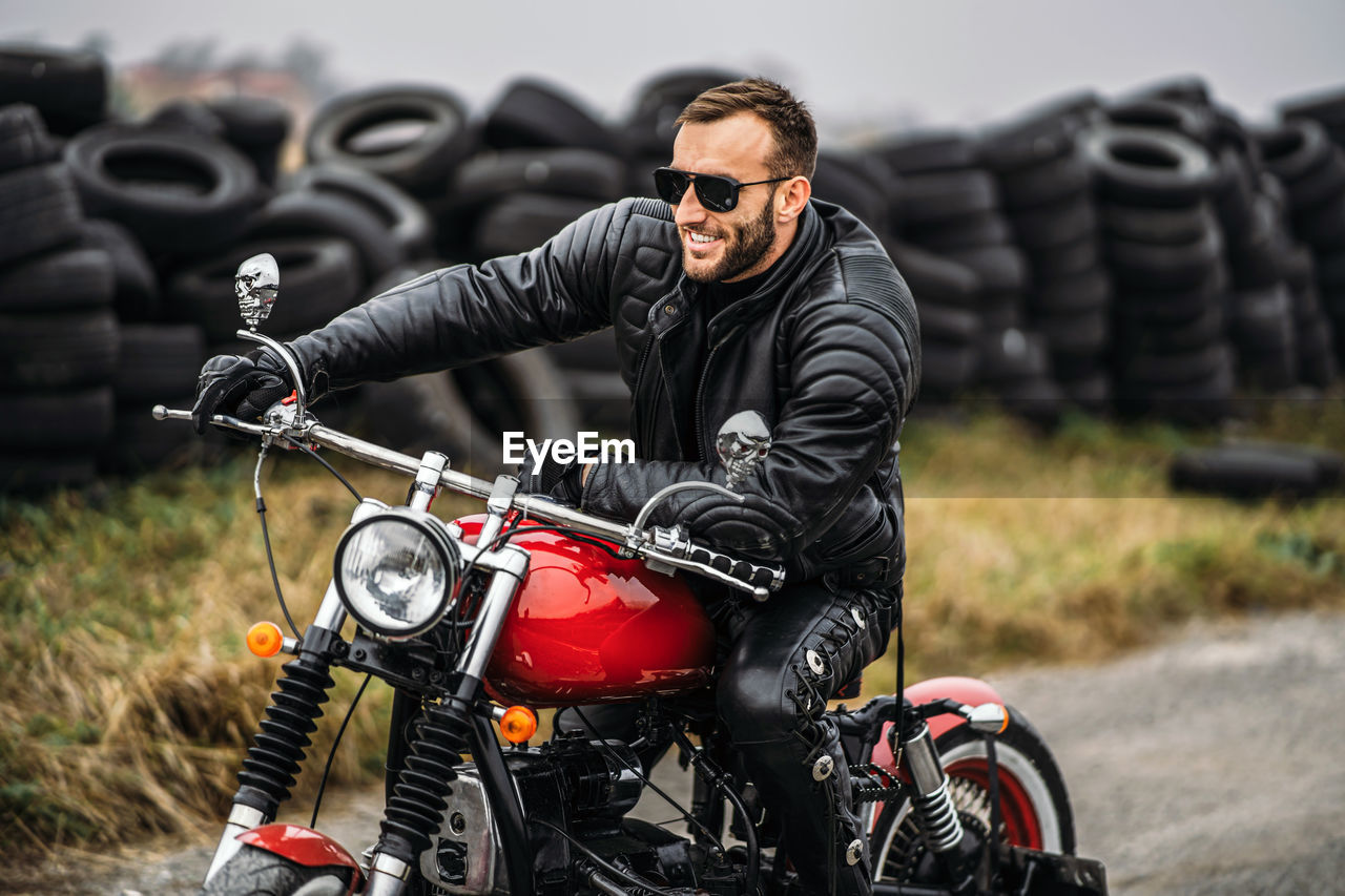 Biker in a leather suit sitting on  a red motorcycle on the road