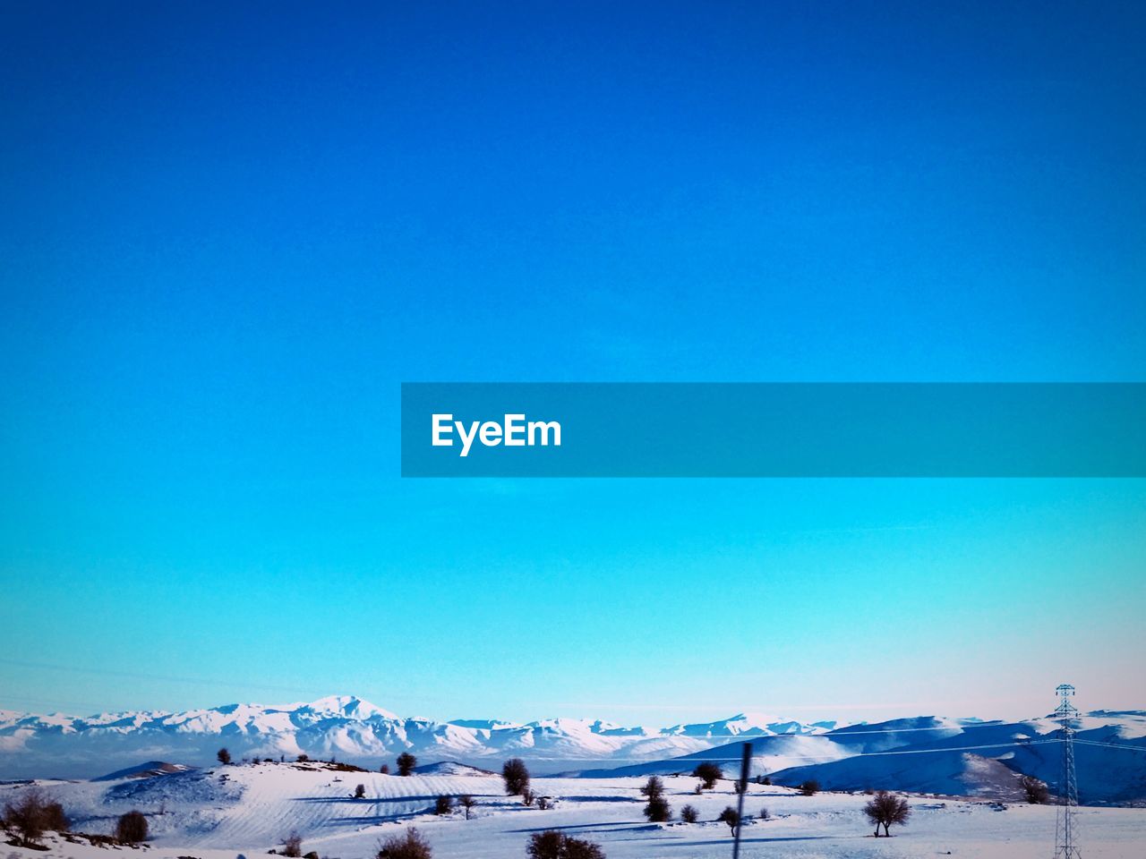 Scenic view of snowcapped mountains against clear blue sky