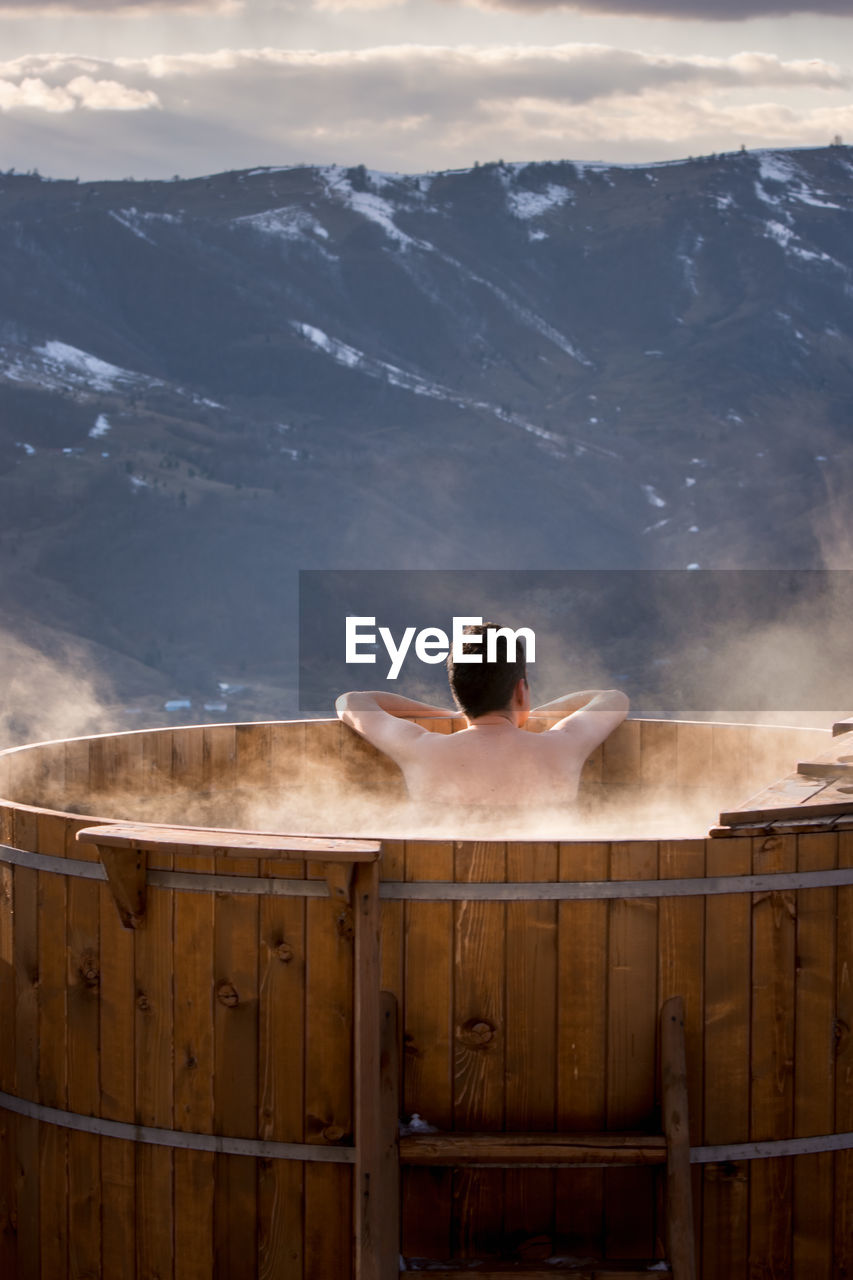 Adult man relaxes in barrel with hot water, in winter, transylva