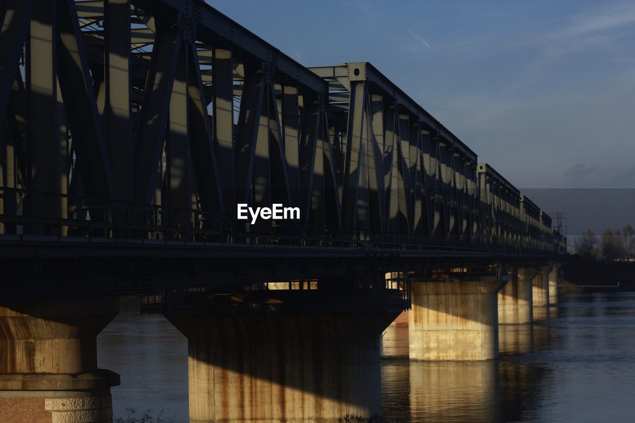 LOW ANGLE VIEW OF BRIDGE OVER RIVER AGAINST SKY