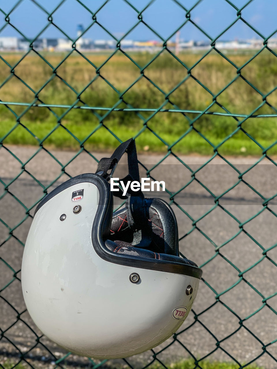 HIGH ANGLE VIEW OF METAL FENCE ON FIELD SEEN THROUGH CHAINLINK