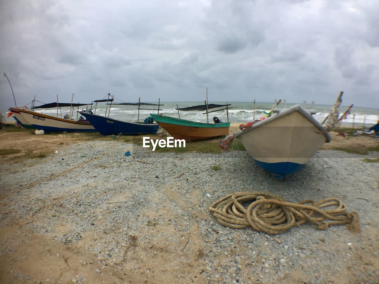 BOATS MOORED AT BEACH AGAINST SKY