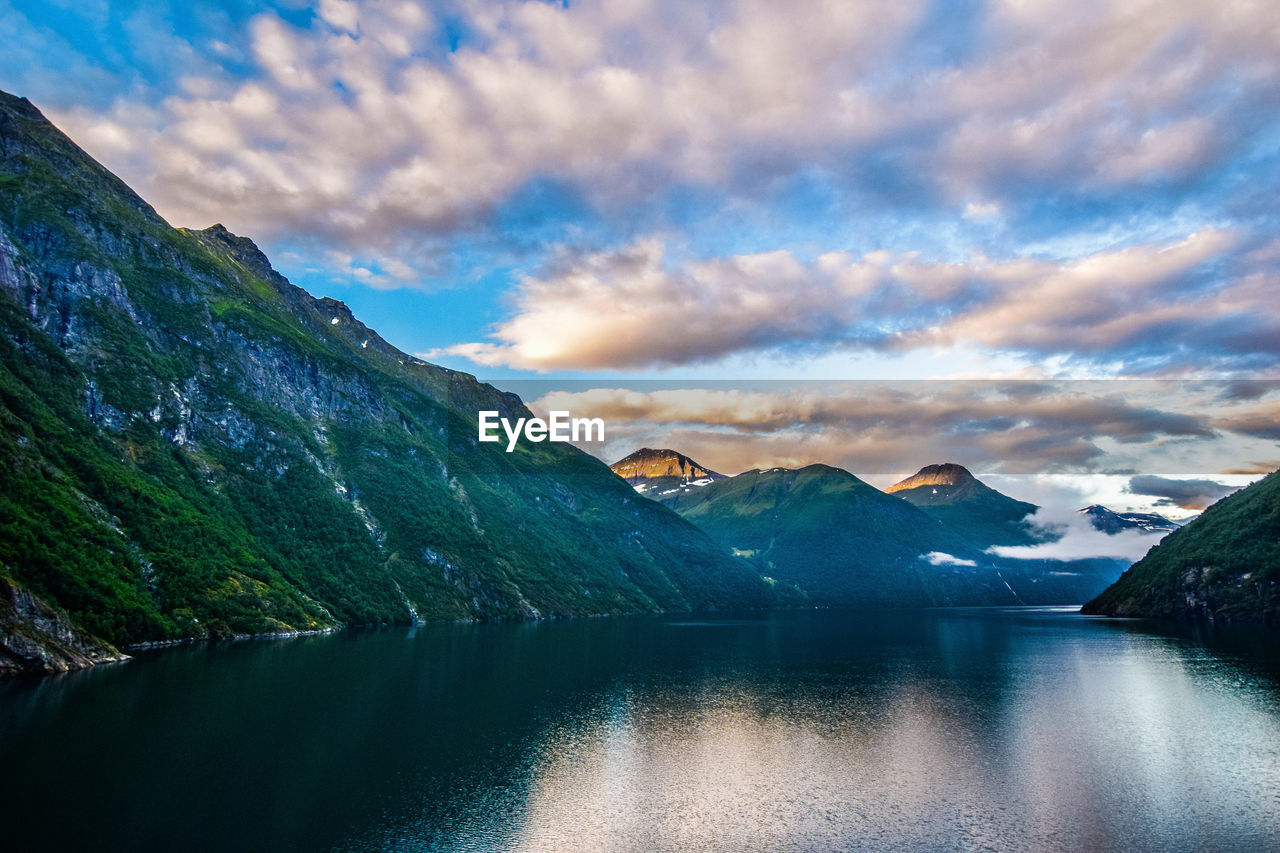 Scenic view of lake by mountains against sky