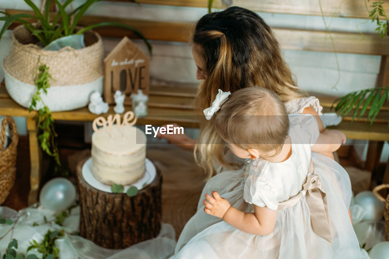 High angle view of mother with daughter looking at cake