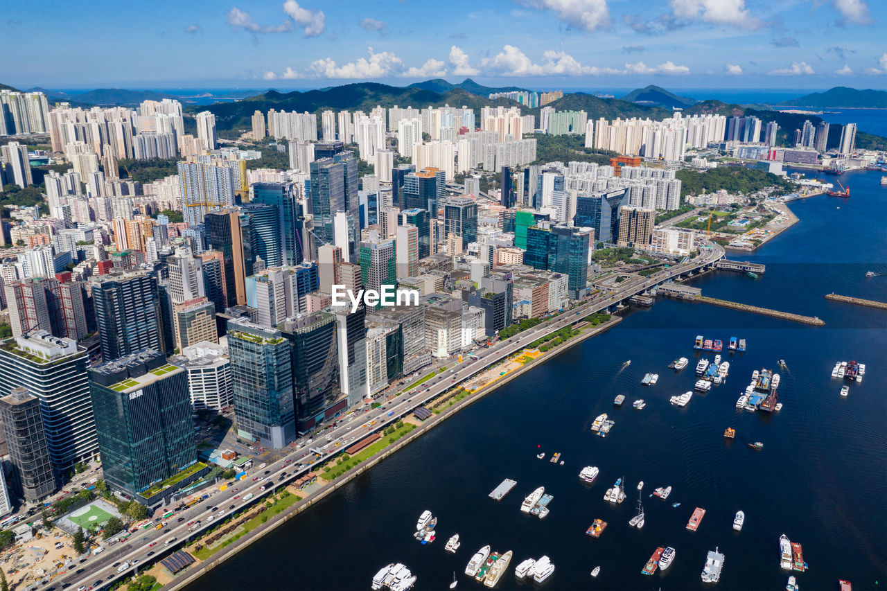 Aerial view of modern buildings by sea against sky