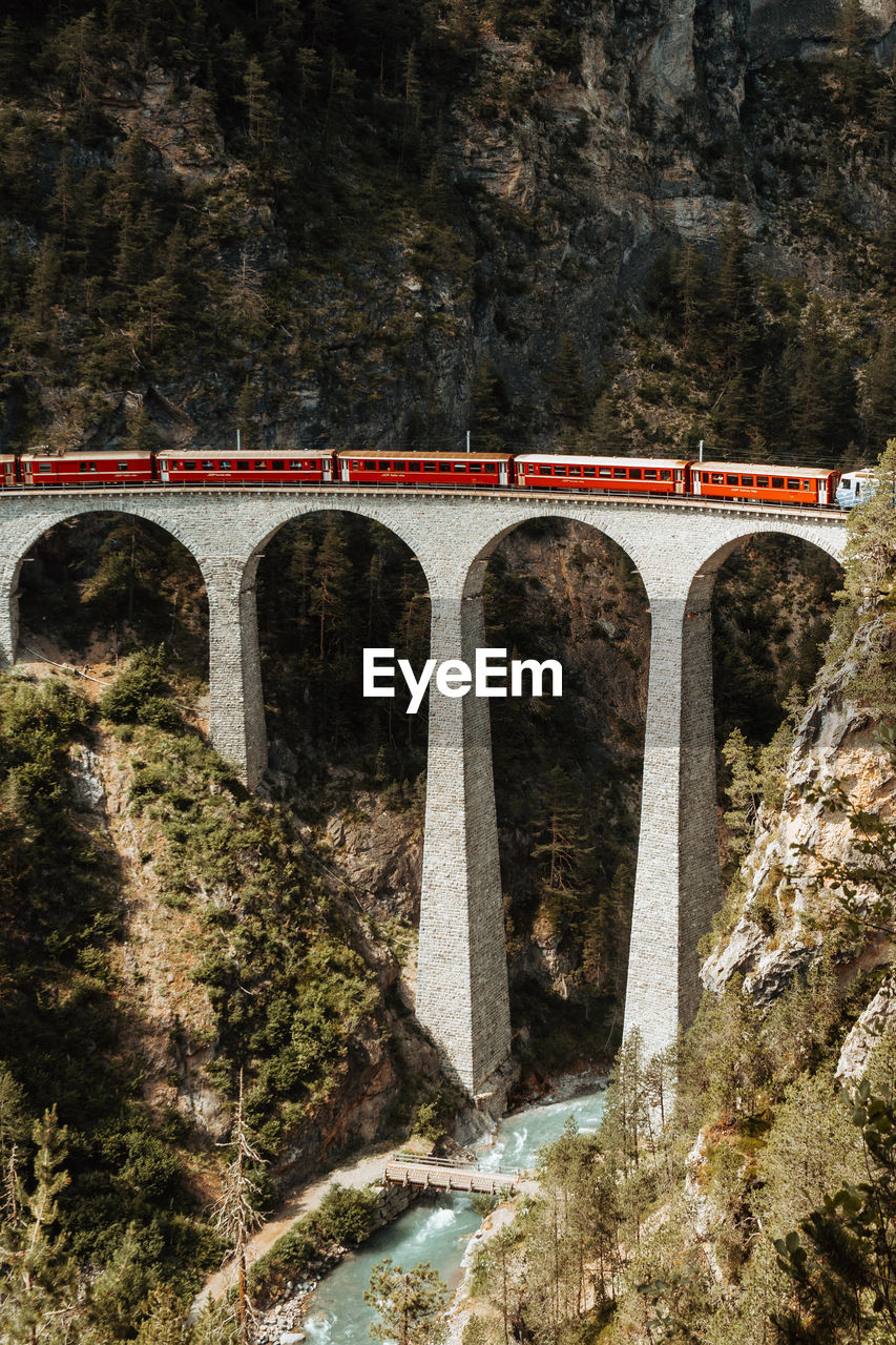 Train on arch bridge by mountains