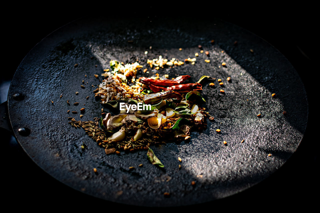 Indian spices being roasted on steel plate for cooking.