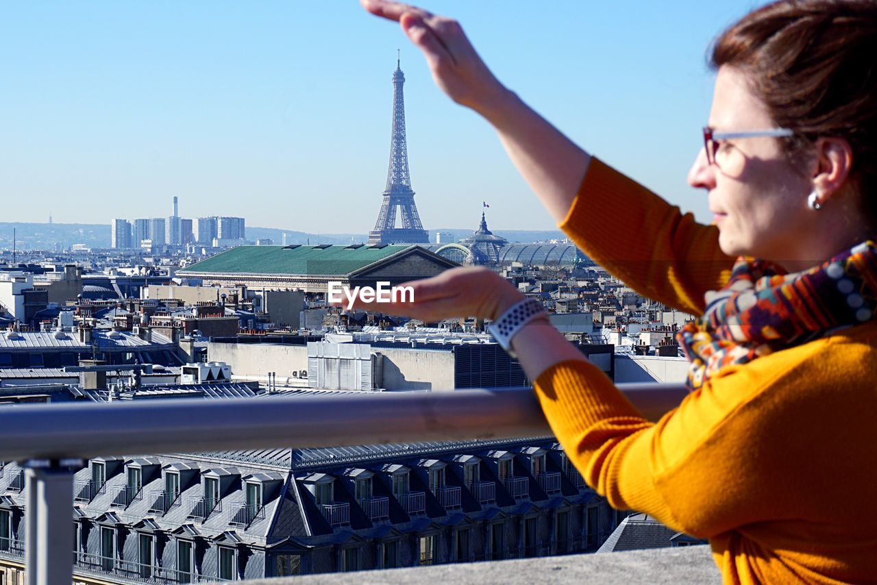 Optical illusion of woman holding eiffel tower against sky