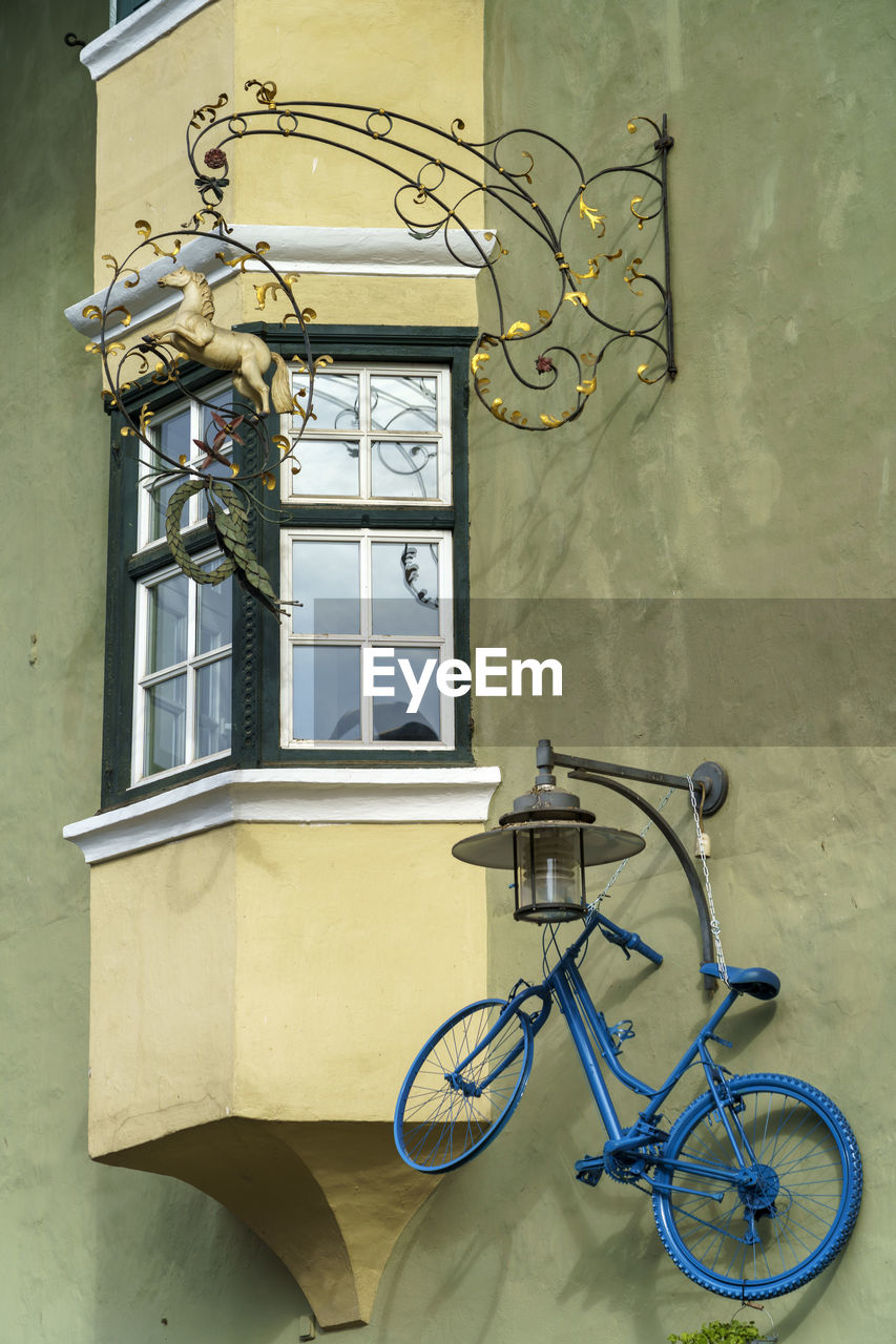 BICYCLE PARKED AGAINST WALL OF BUILDING