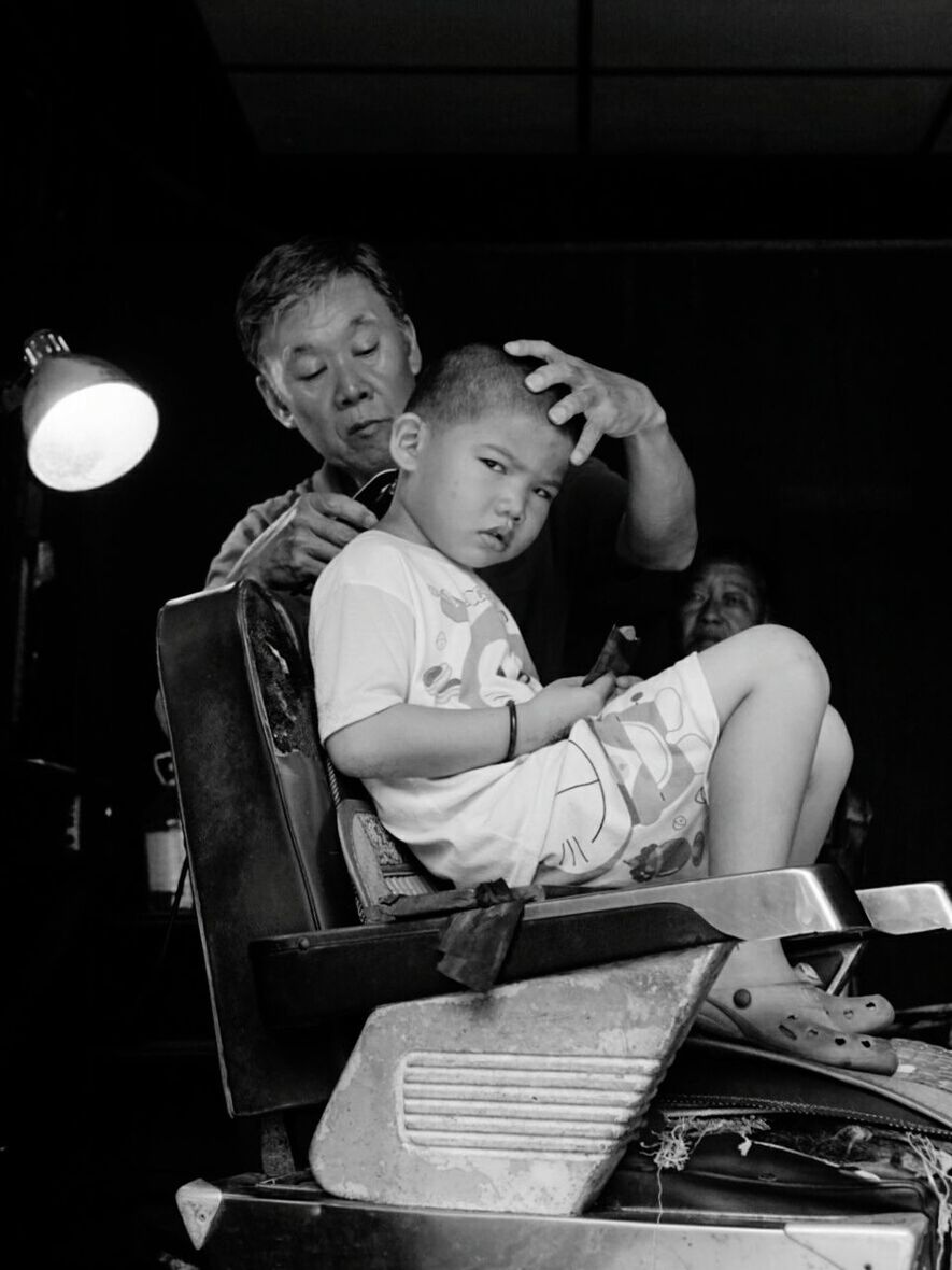 REAR VIEW OF A YOUNG MAN SITTING ON TABLE