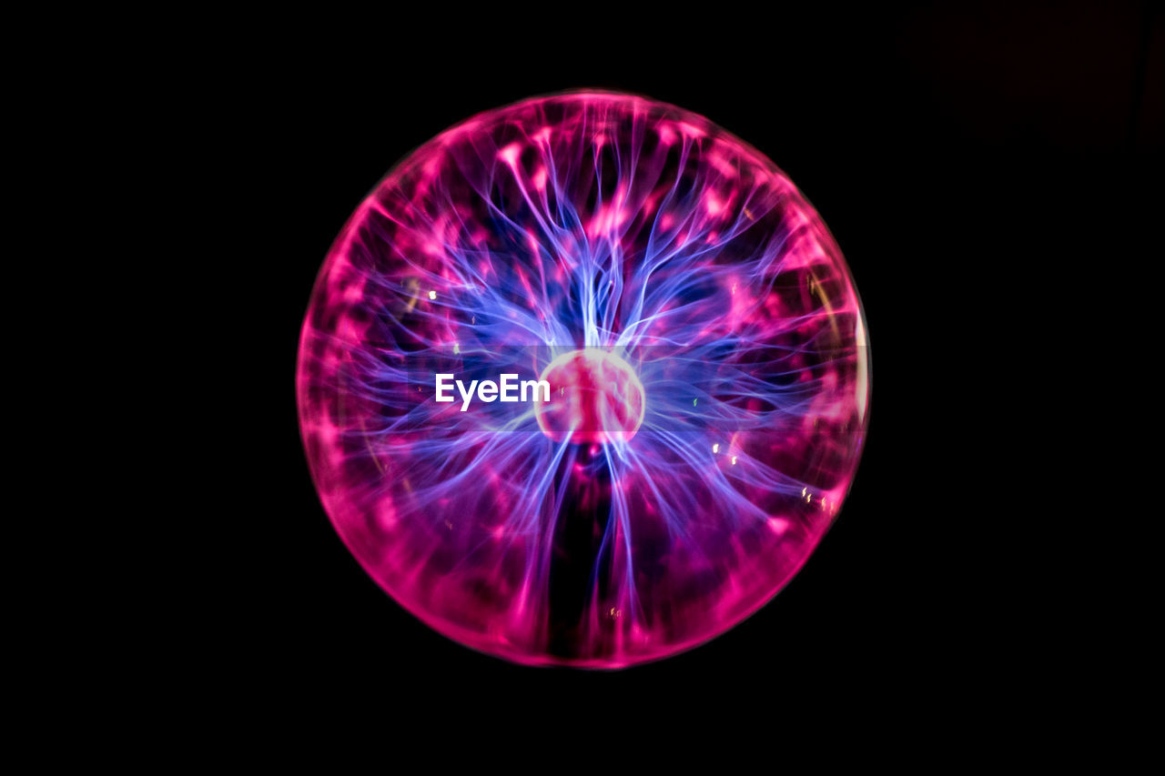 Close-up of illuminated plasma globe against black background