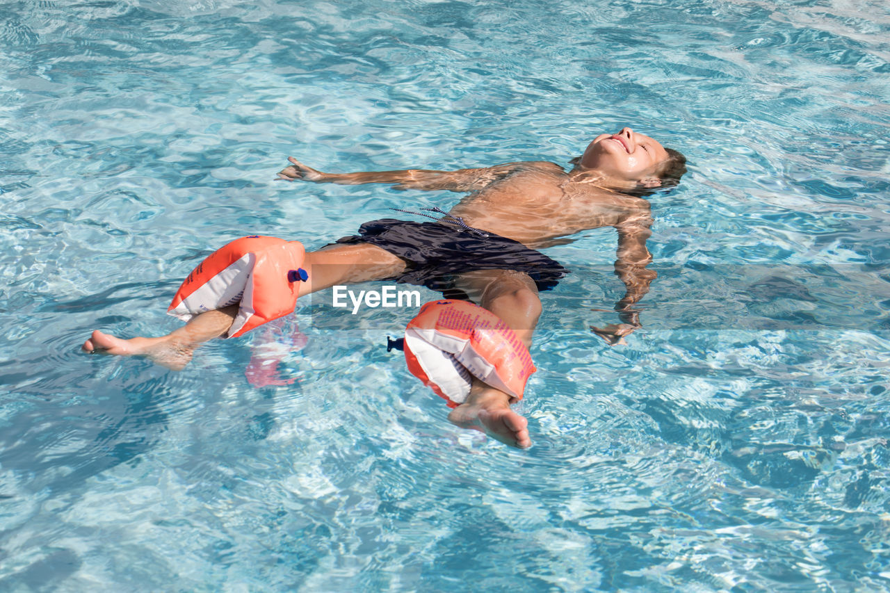 HIGH ANGLE VIEW OF TWO MEN SWIMMING IN POOL