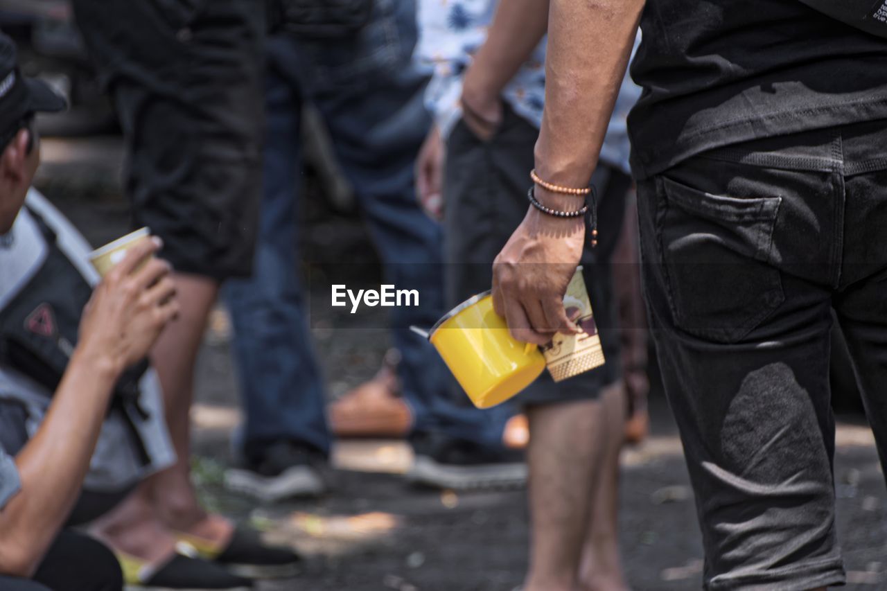 MIDSECTION OF MAN HOLDING HANDS ON STREET