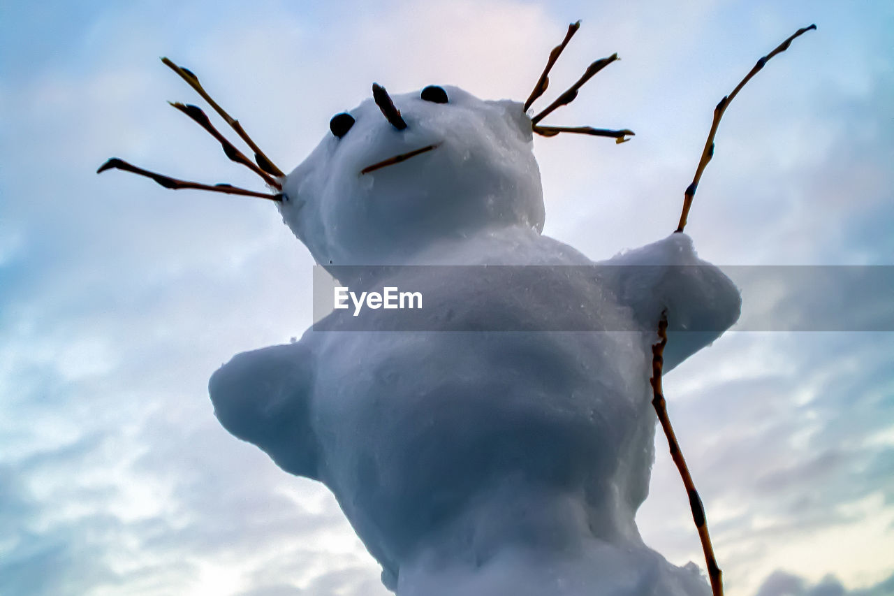 Low angle view of snowman against sky