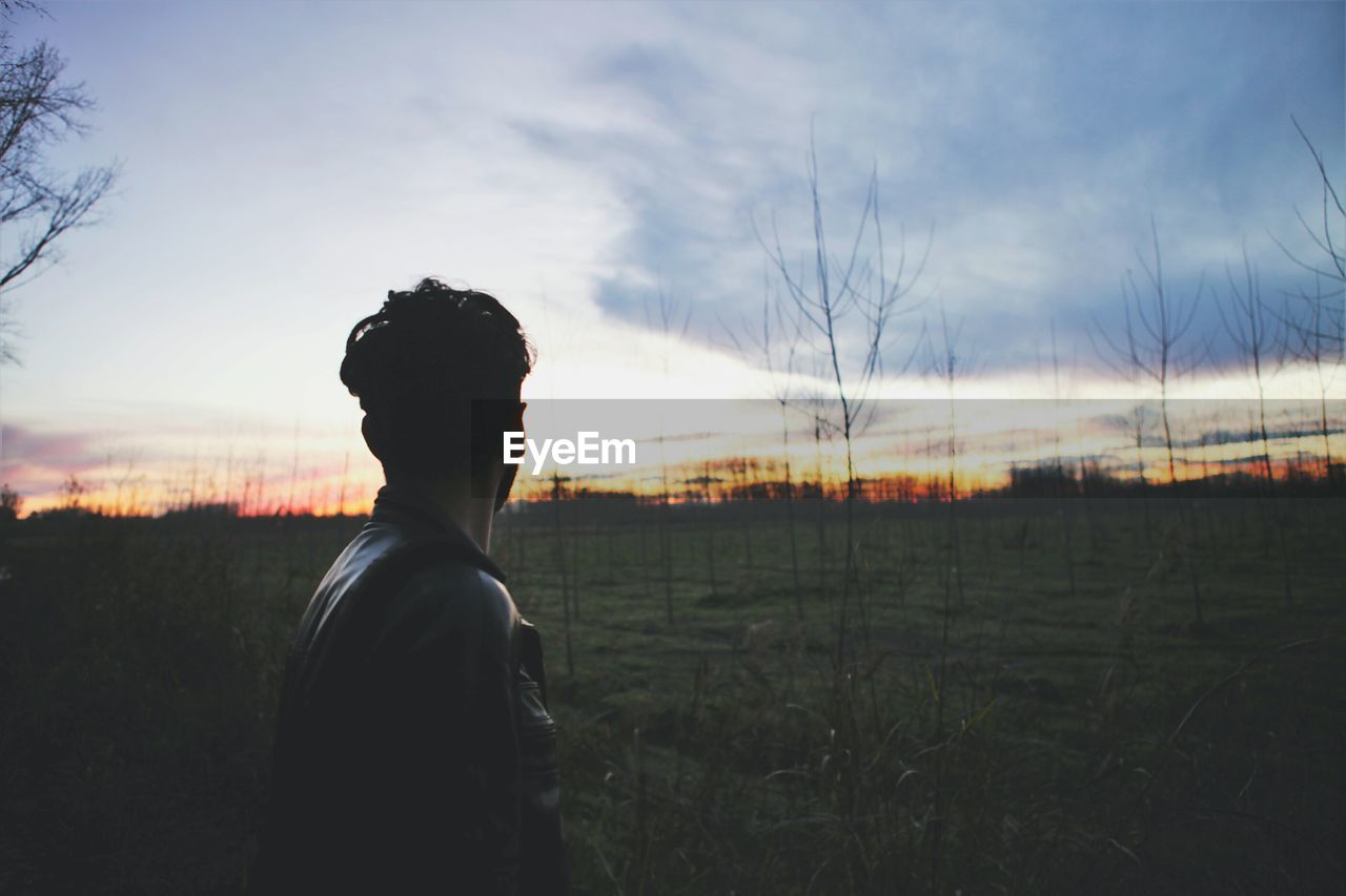 Man standing on field against sky during sunset