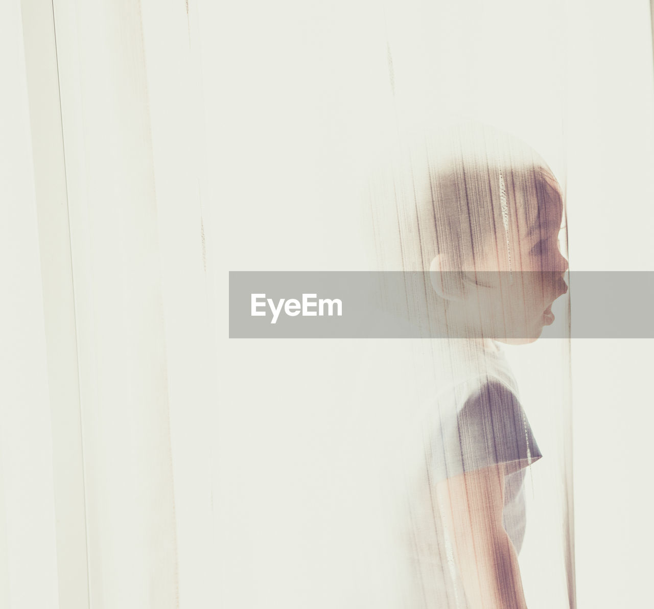 Boy with mouth open standing behind curtain