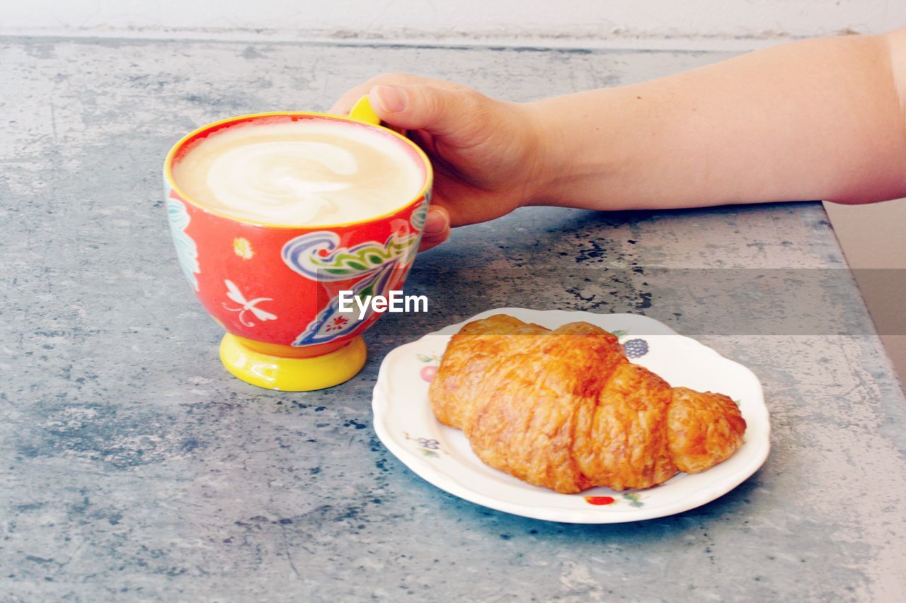 Cropped image of person having breakfast on table