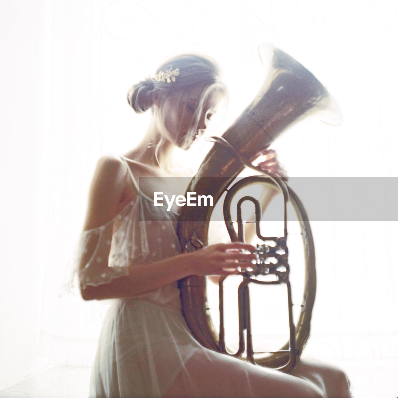 Woman with saxophone sitting against white background