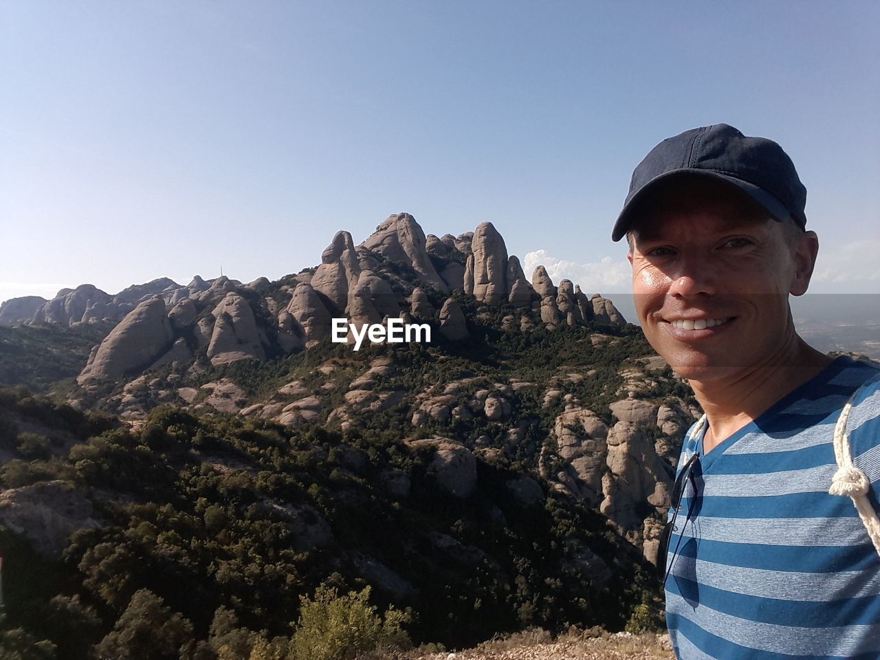 Portrait of man smiling while standing against mountains