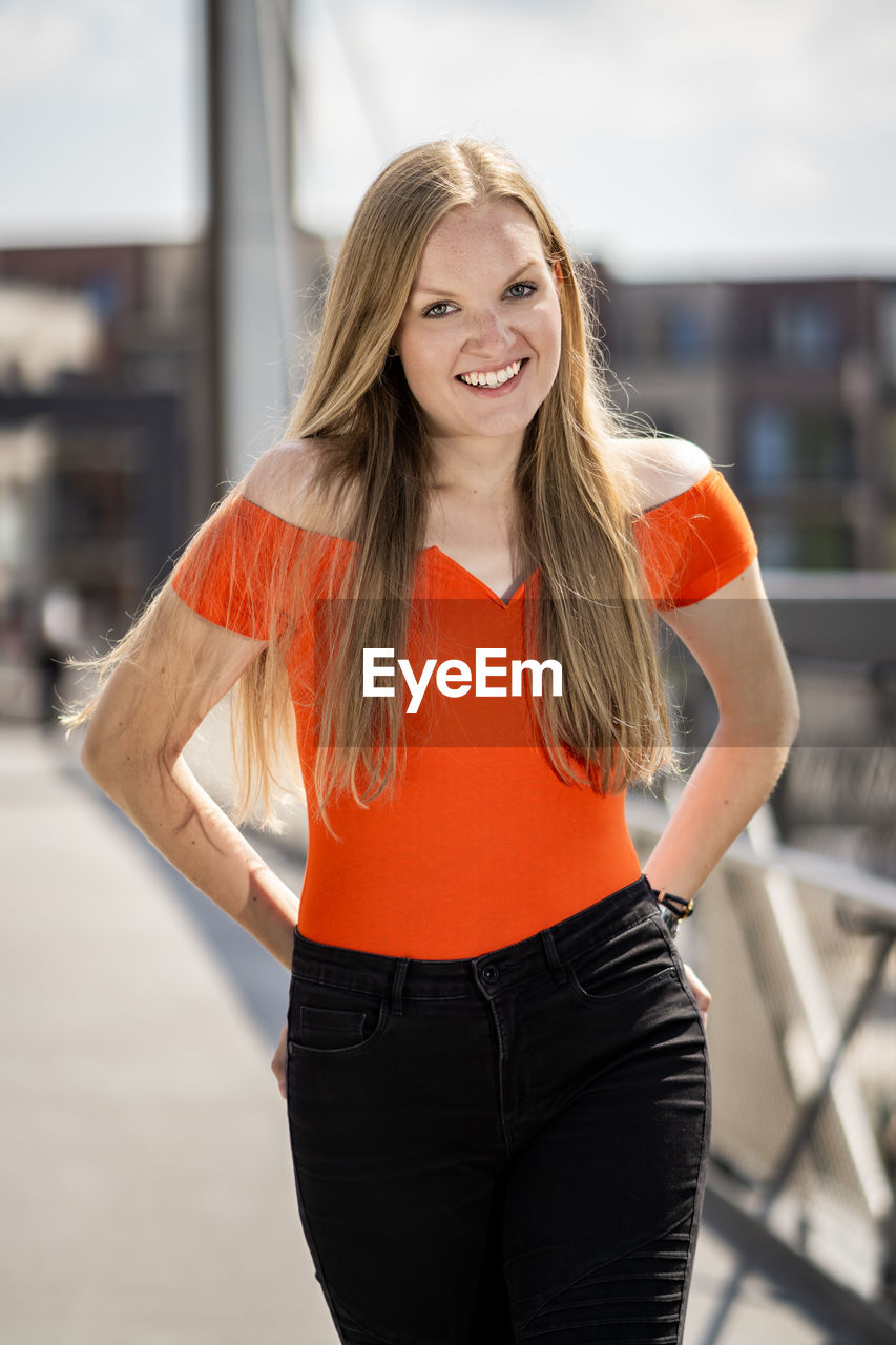 Portrait of smiling young woman standing in city