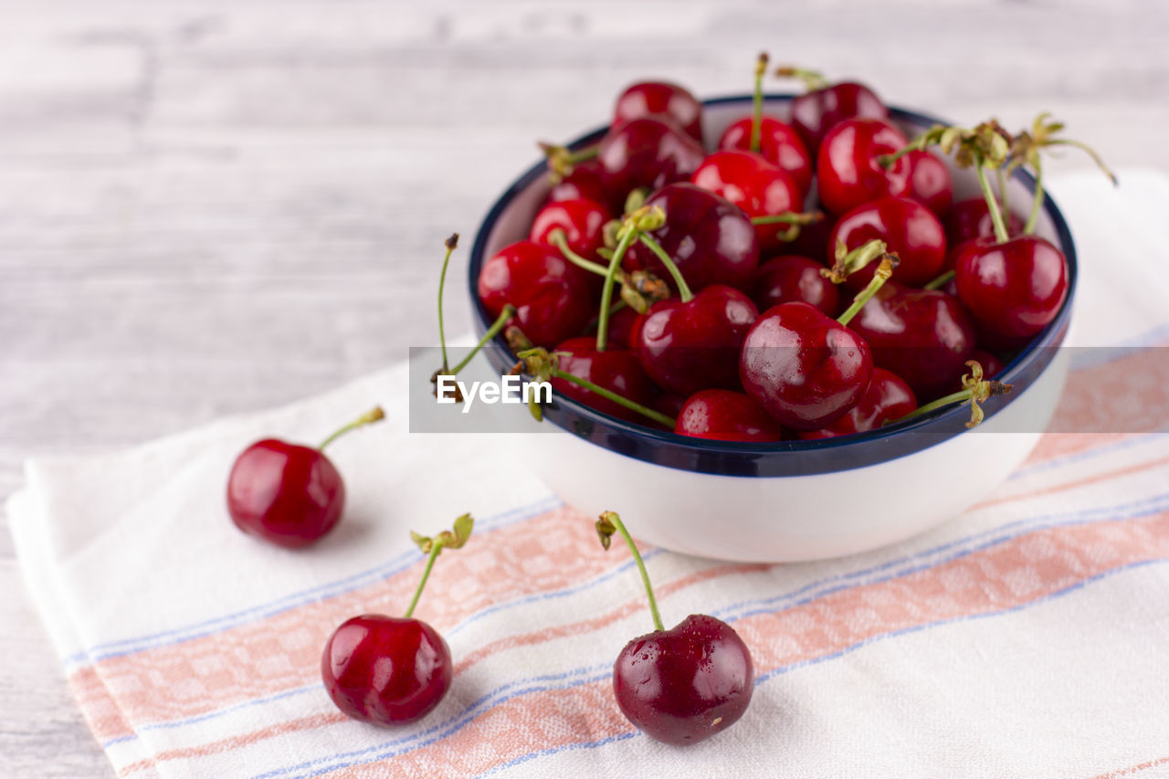 Fresh cherry on the white wooden table. ripe sweet berries in droplets of water