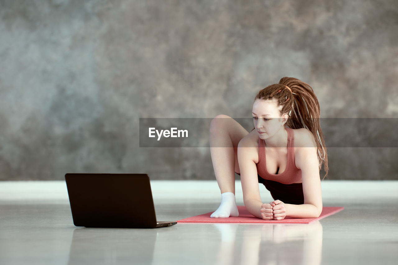 side view of woman using laptop while sitting on table