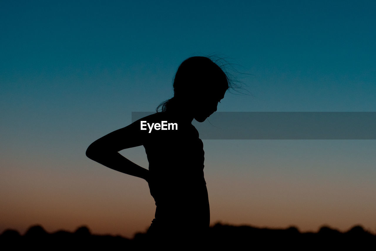 Young girls silhouette against a summer sunset sky