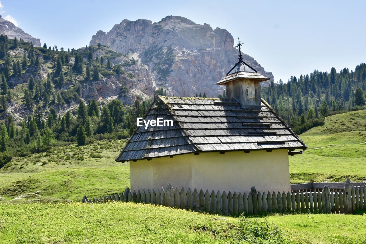 BUILT STRUCTURE ON FIELD AGAINST MOUNTAINS
