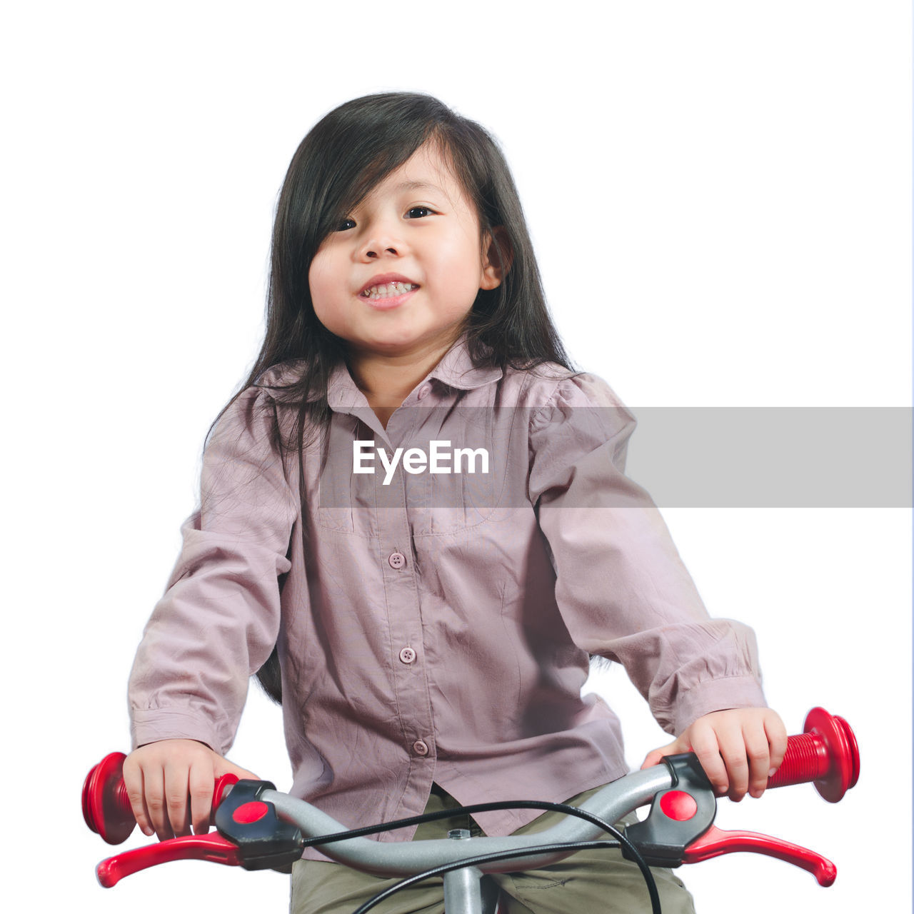 Portrait of smiling girl sitting on bicycle against white background